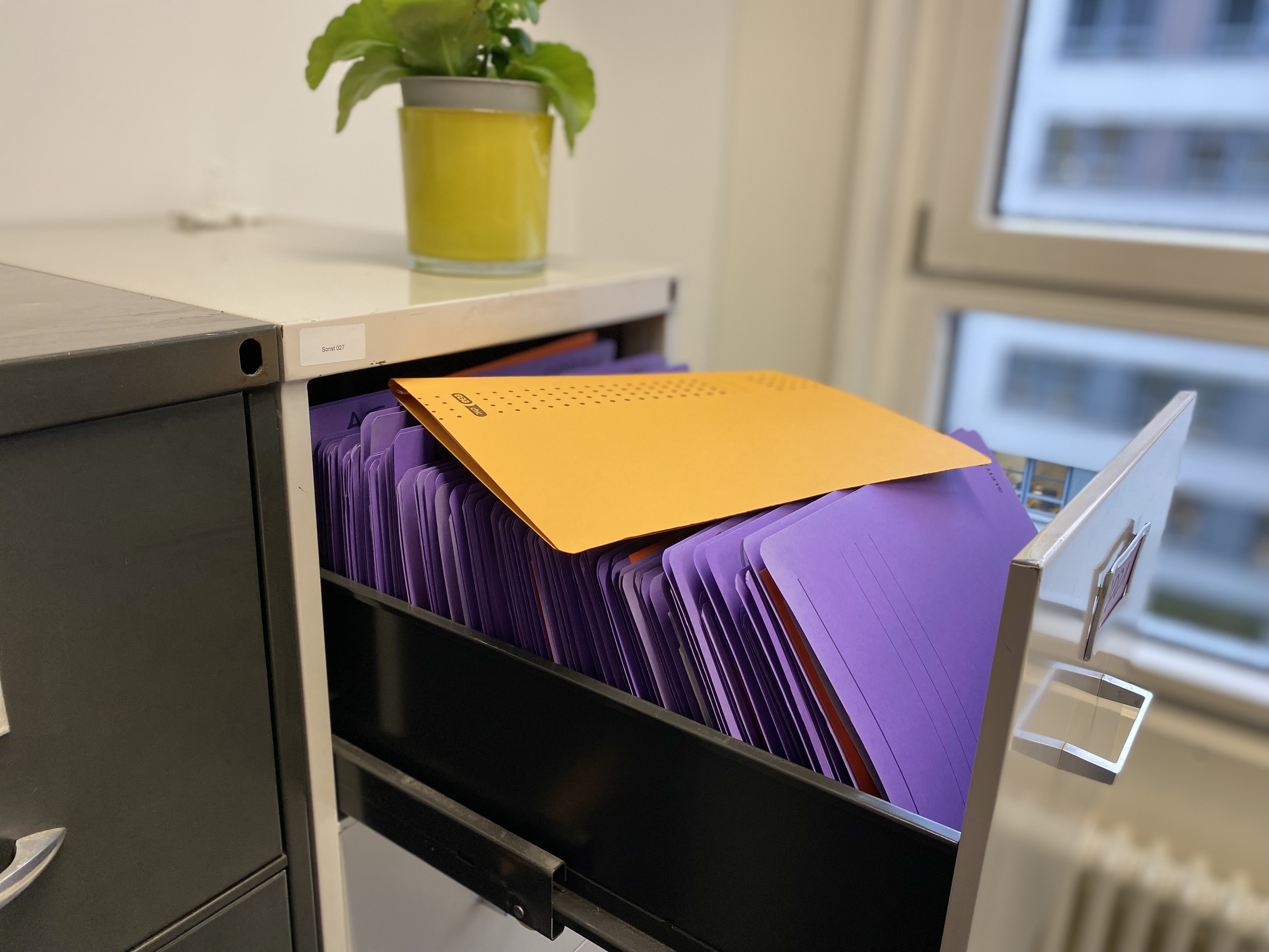 Das Bild zeigt eine Fallakte, die auf einem geöffneten Aktenschrank liegt –